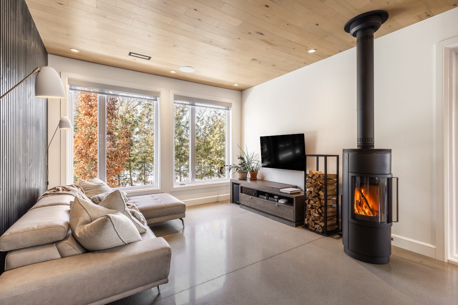 Salon avec foyer au bois pivotant et plafond de bois clair